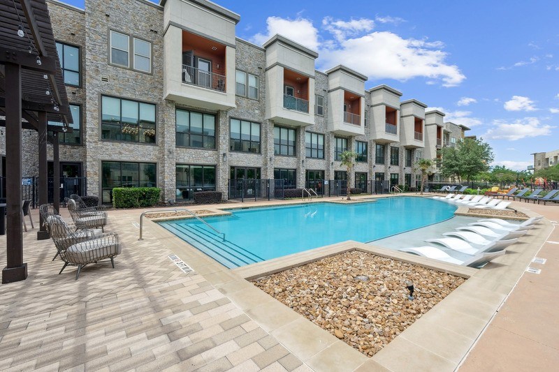 A large swimming pool with lounge chairs.