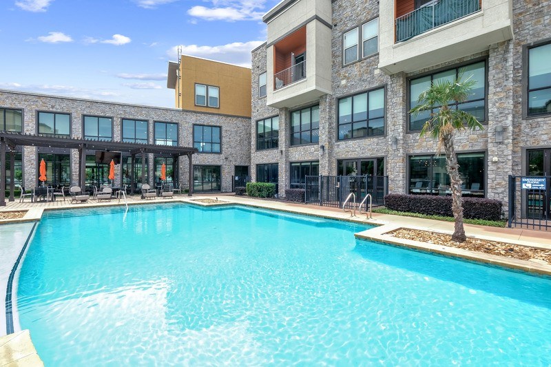 A large swimming pool in front of a multi-story building.
