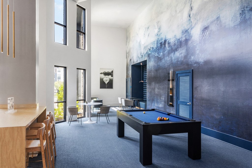 A room with a pool table and a wall with a painting.