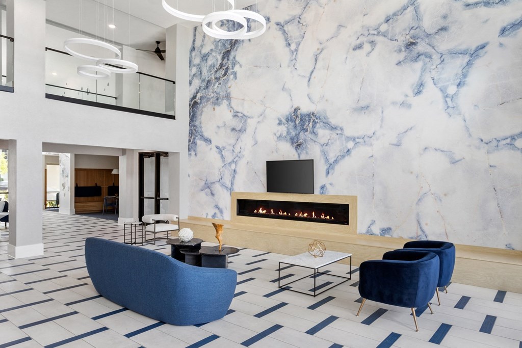 A modern living room with a fireplace and blue chairs.