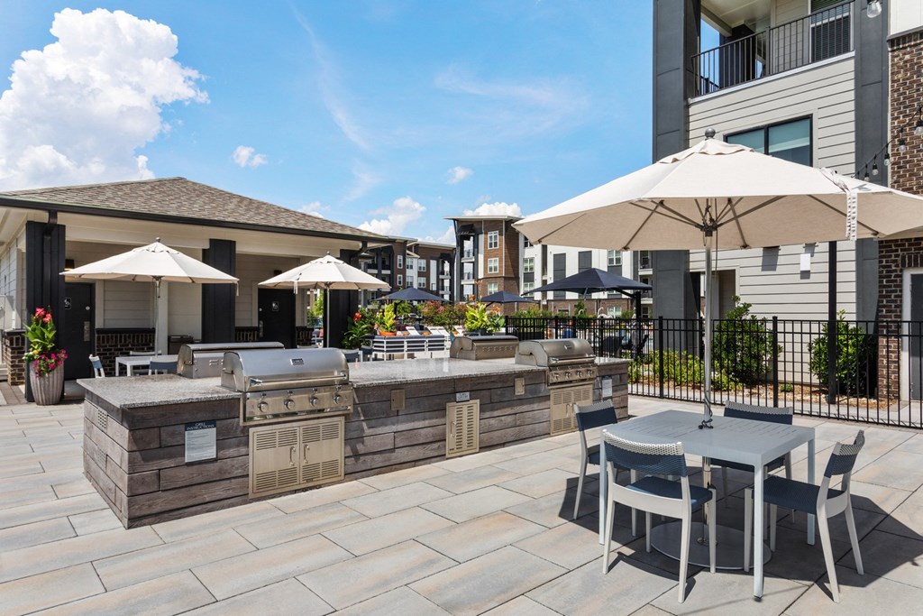 A patio with a table and chairs and umbrellas.