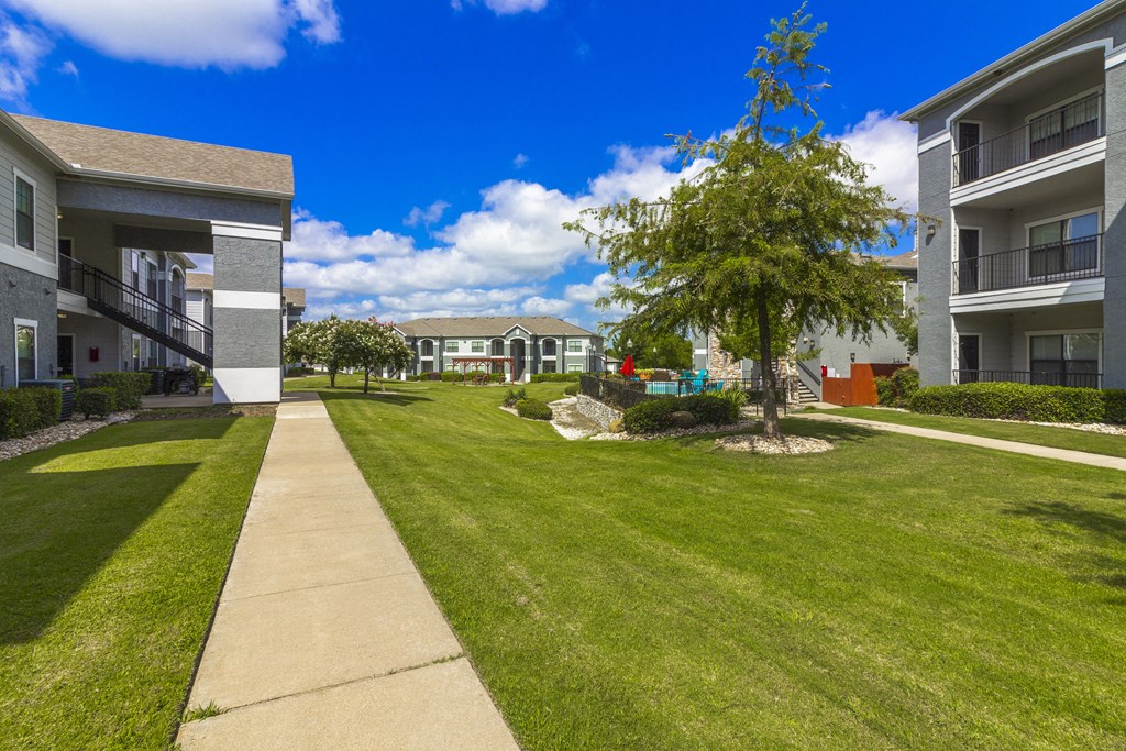 a view of a grassy area between two apartment buildings