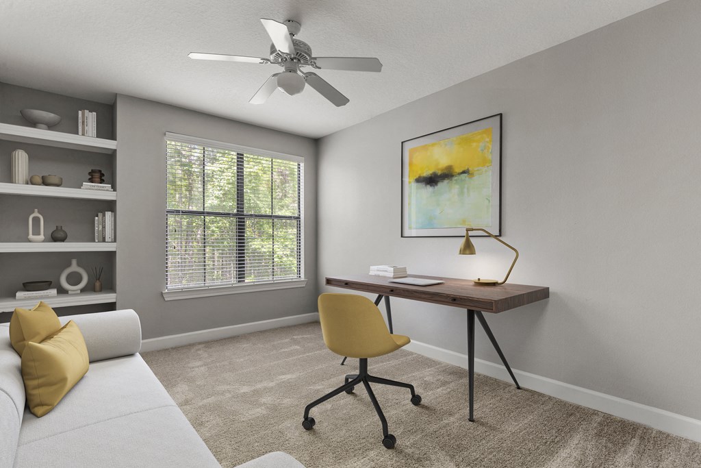 an office with a desk and a ceiling fan in a living room
