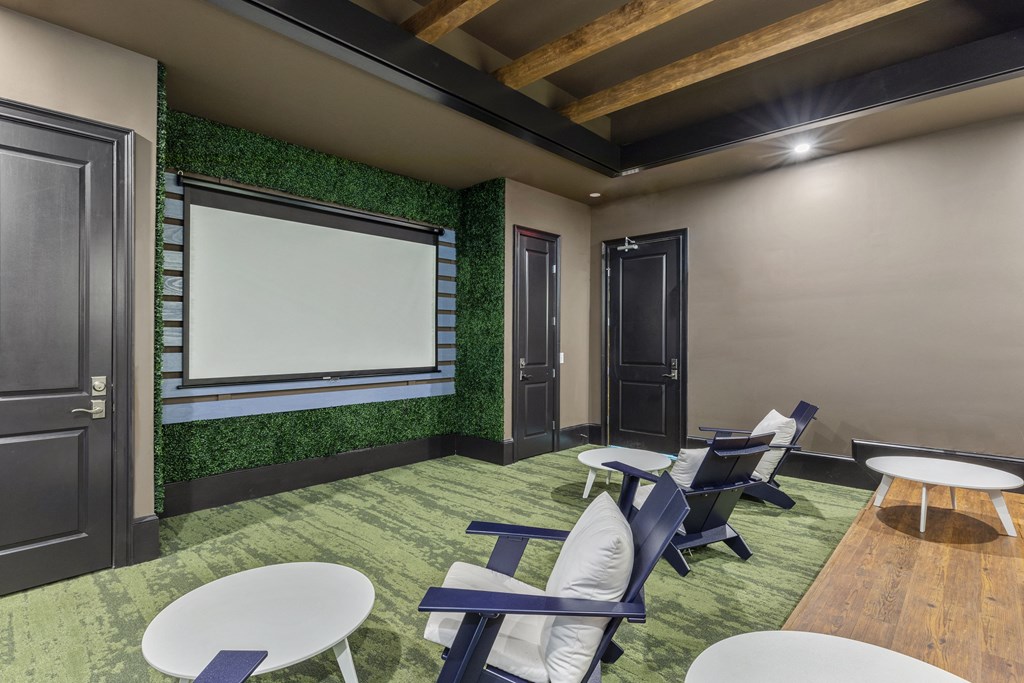 a lounge area with chairs and tables and a projector screen