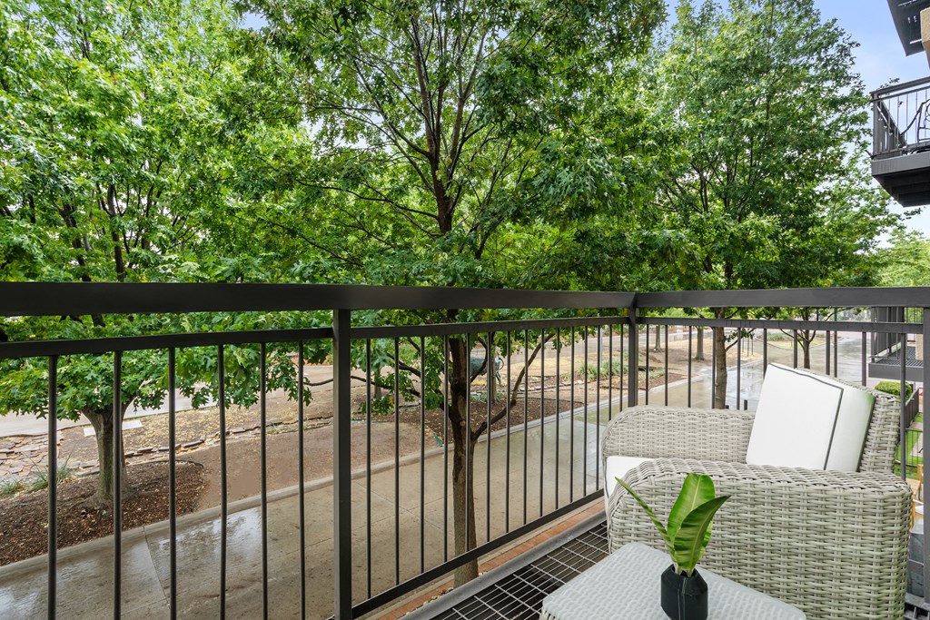 a balcony with a table and chairs and trees