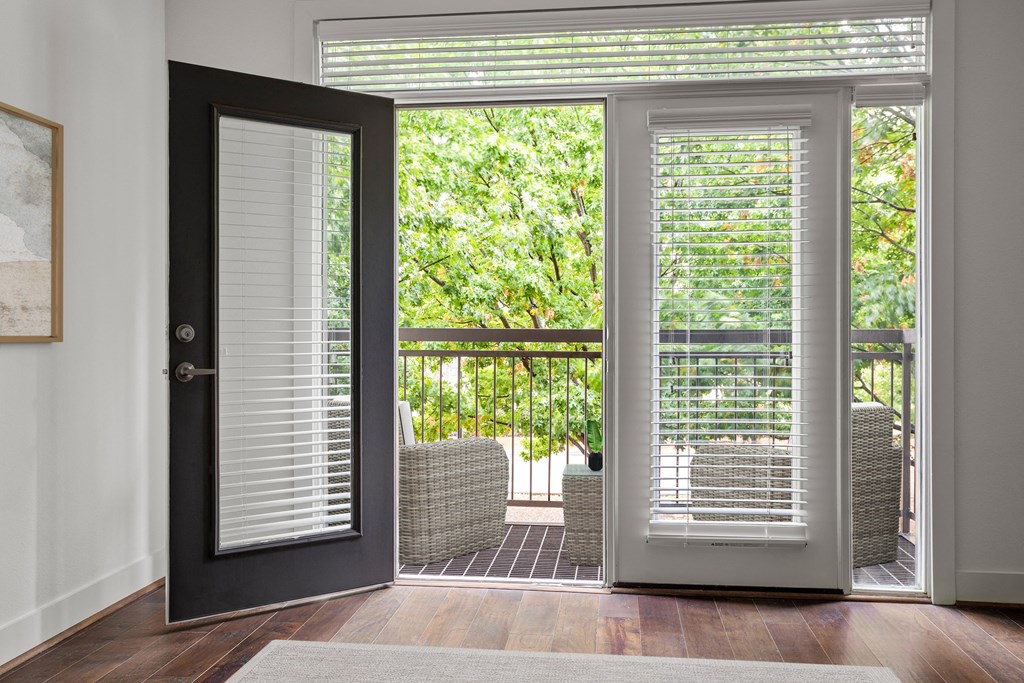 a living room with a door to a balcony with chairs