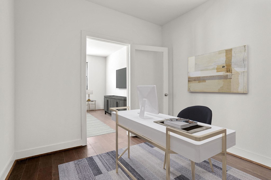 a living room with a white desk and a door to a bedroom