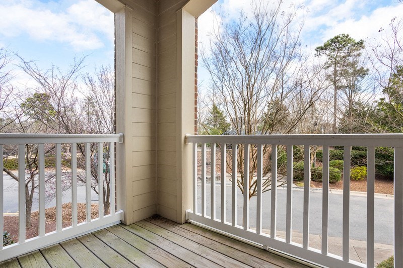 a balcony with a view of a parking lot and trees