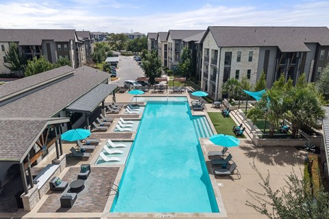 A large swimming pool surrounded by lounge chairs and umbrellas.