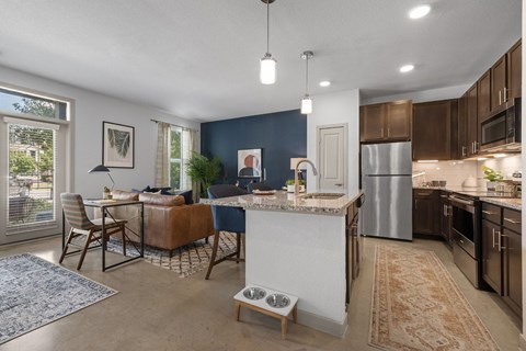 A kitchen with a white island and brown chairs.
