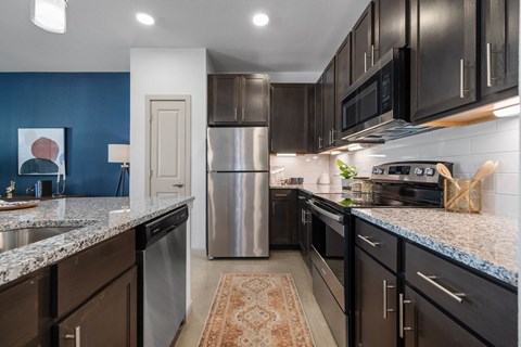 A kitchen with dark brown cabinets and a blue wall.
