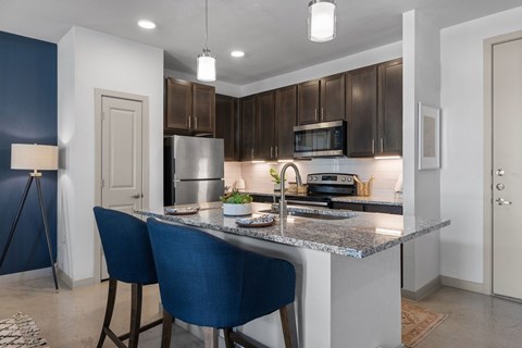 A kitchen with a blue chair and a granite counter.
