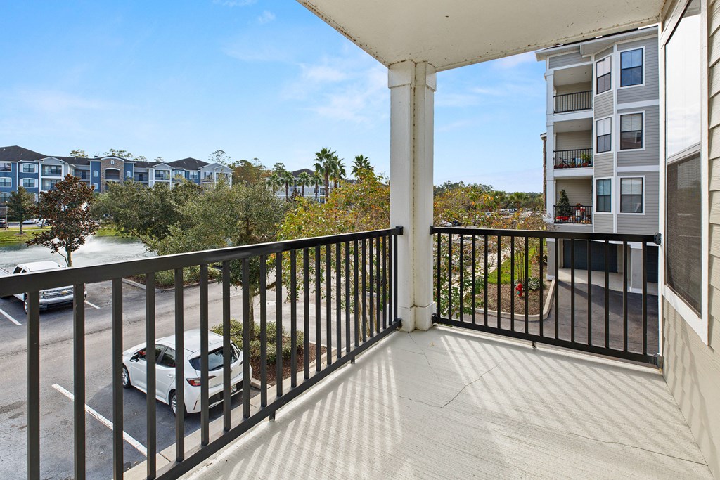 the view from the balcony of an apartment building with a car parked on the street
