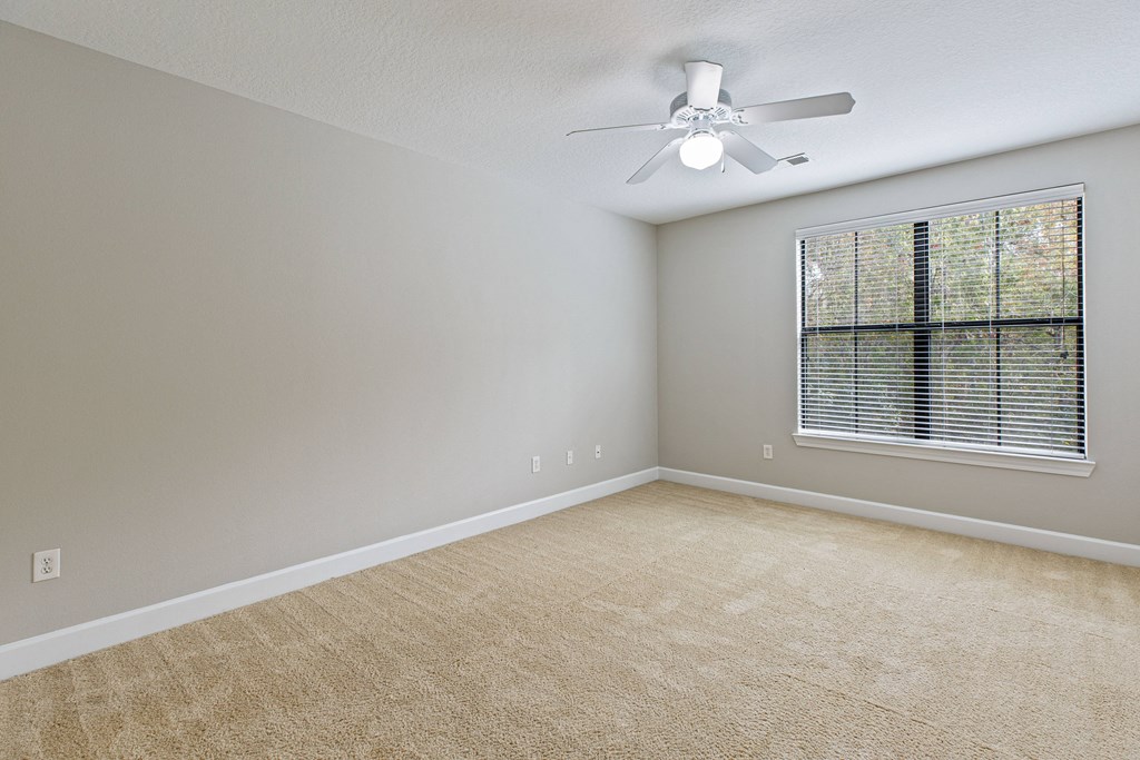 an empty living room with a ceiling fan and a window