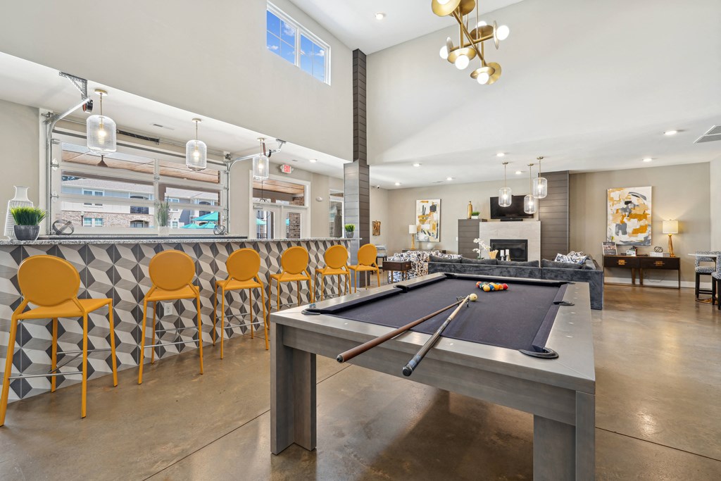 a clubhouse with a pool table and a bar with yellow chairs