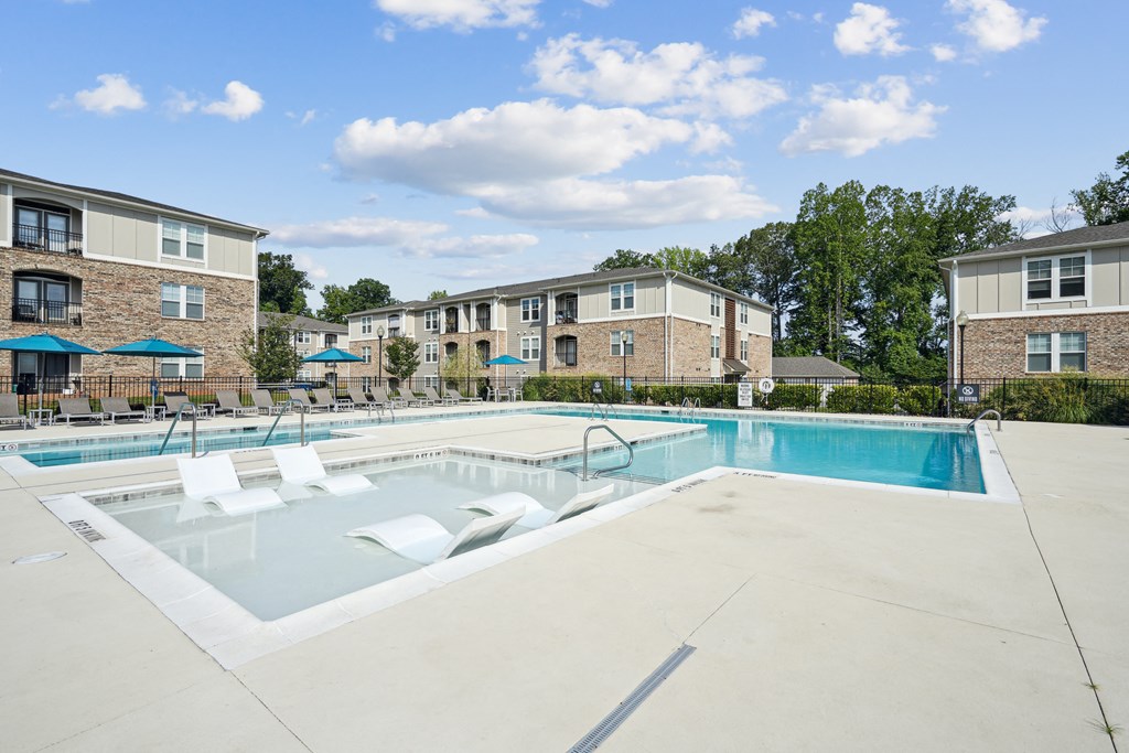 pool with lounge chairs in front of apartment building