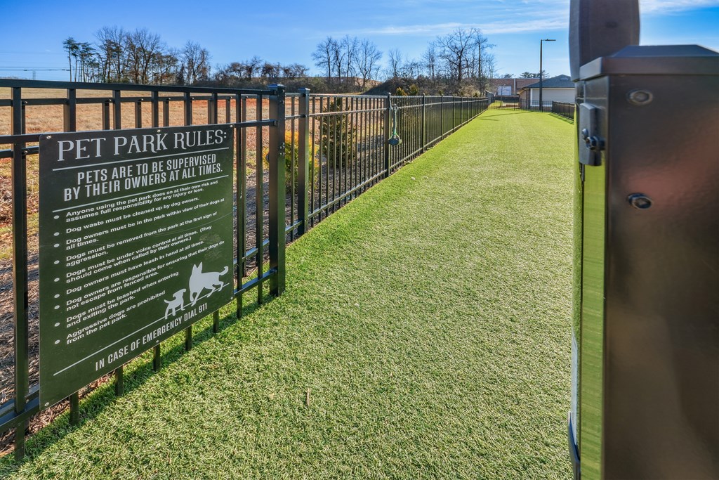 a sign for pet park rules in front of a fence