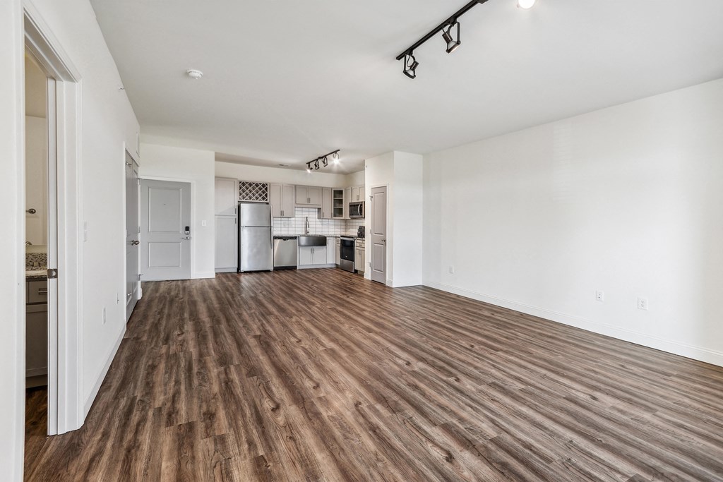 an empty living room and kitchen with a wood floor