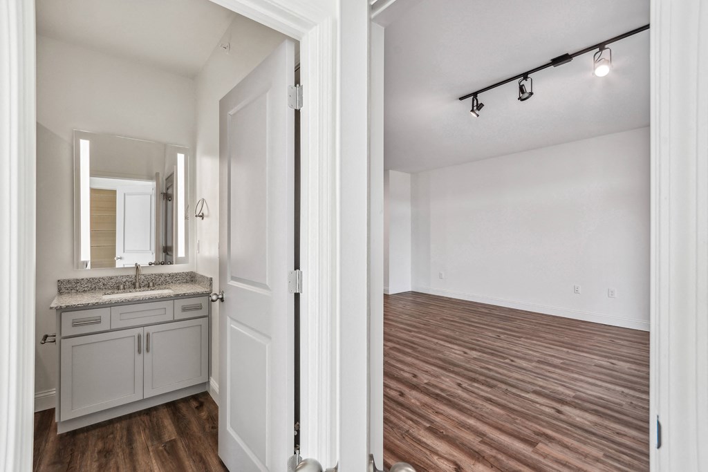 the living room and kitchen of a renovated apartment with wood flooring
