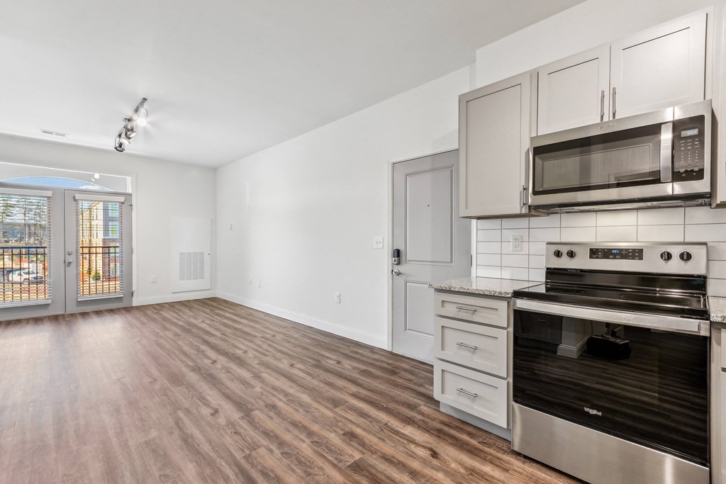 the living room of an apartment with a stove and a microwave