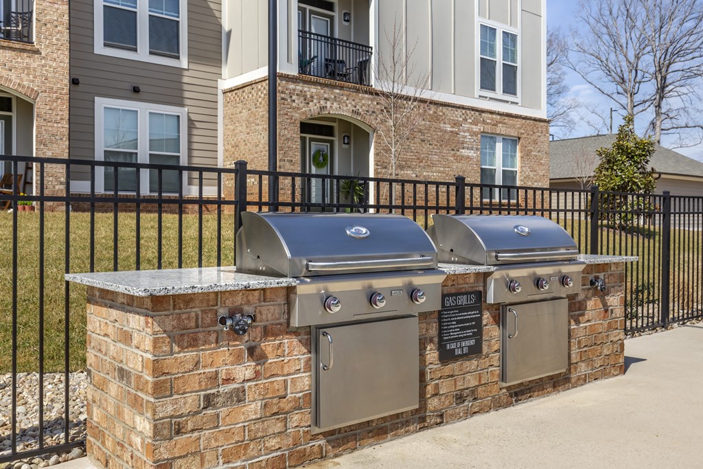 two stainless steel barbecue grills in front of a house