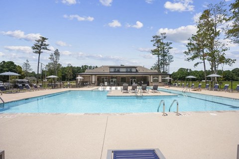 a swimming pool with chairs and a building in the background