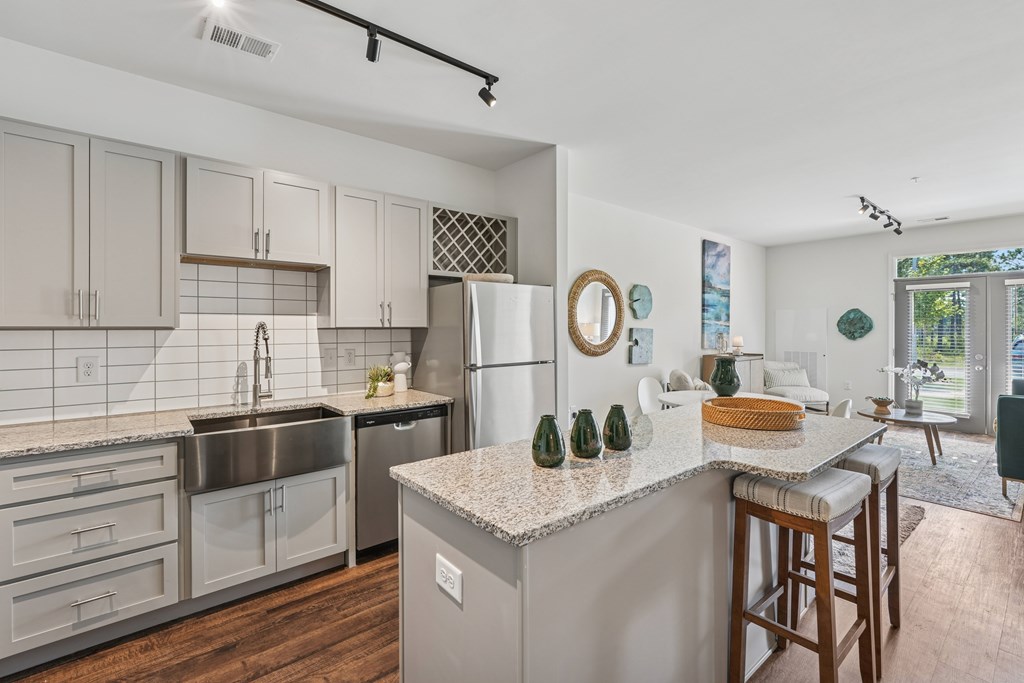A kitchen with a refrigerator, sink, and bar stools.