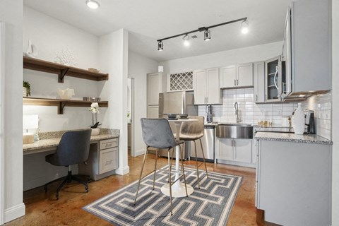 A kitchen with a desk and chairs in the middle.