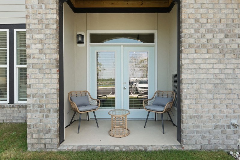 the front porch of a house with two chairs and a table