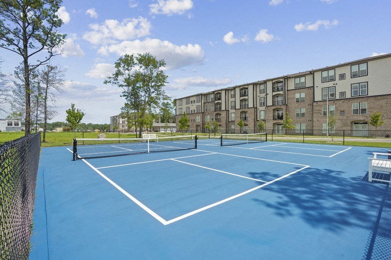 a tennis court with an apartment building in the background