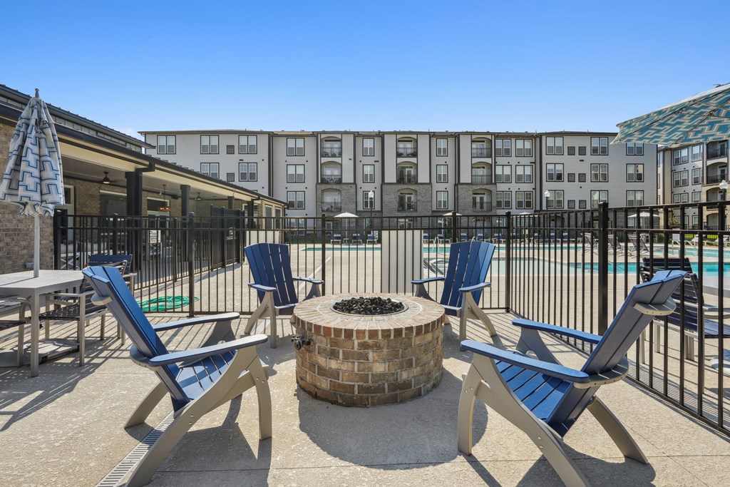 A poolside area with a fire pit and lounge chairs.