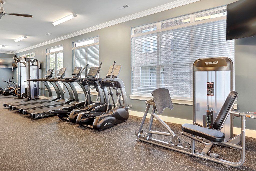 a gym with cardio equipment and weights on the floor