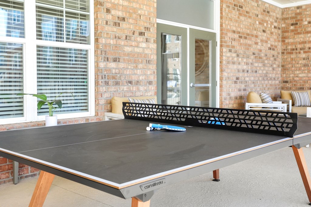 a patio with a ping pong table and a brick wall