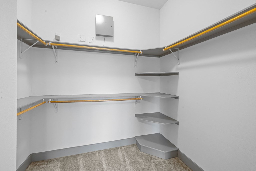 a walk in closet in a room with white walls and shelves