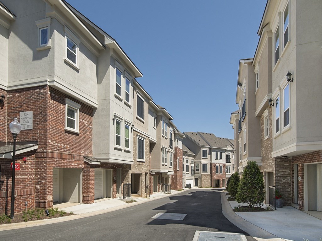 an empty street in an apartment community with brick buildings