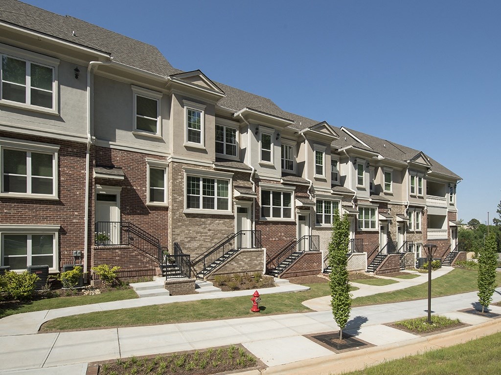 a row of brick apartment buildings with stairs and a red fire hydrant