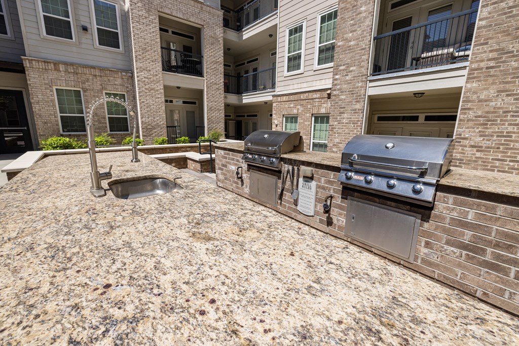 an outdoor kitchen with two grills and a sink