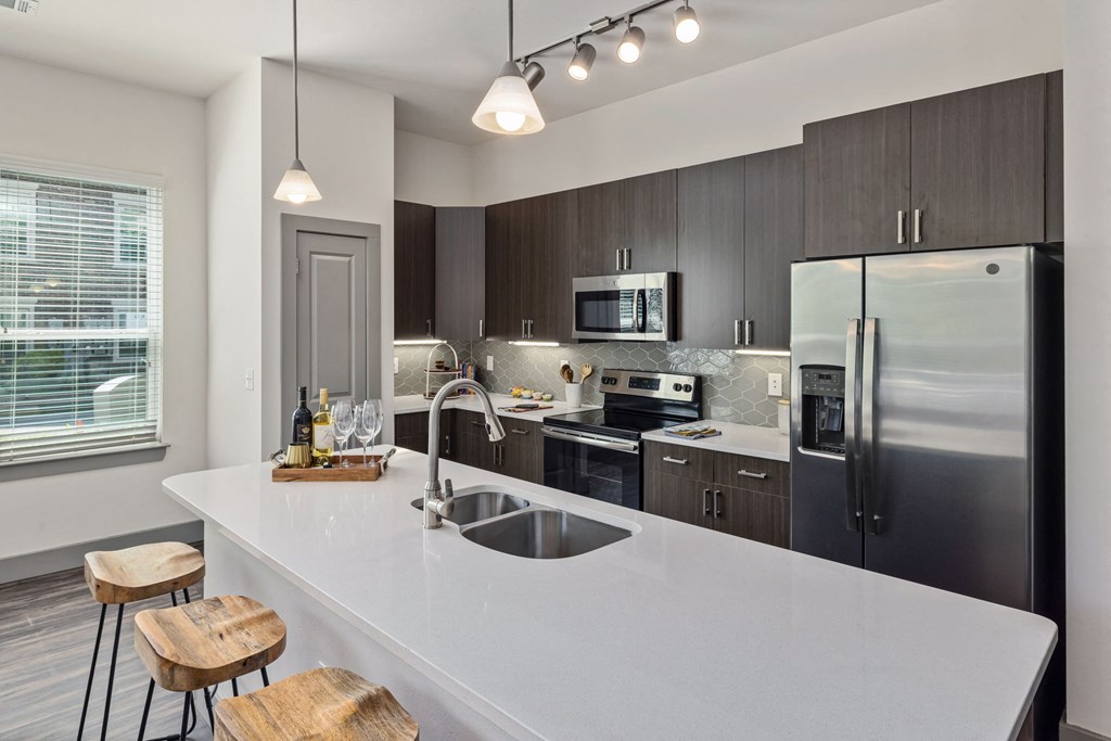 a kitchen with a large white island and stainless steel appliances