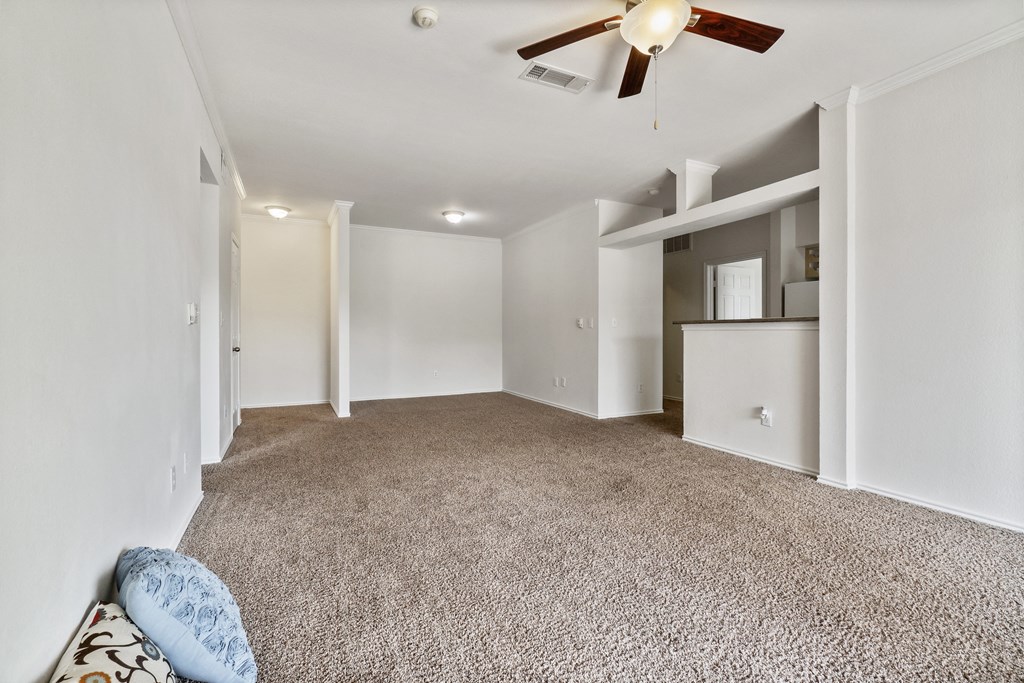 an empty living room with white walls and a ceiling fan