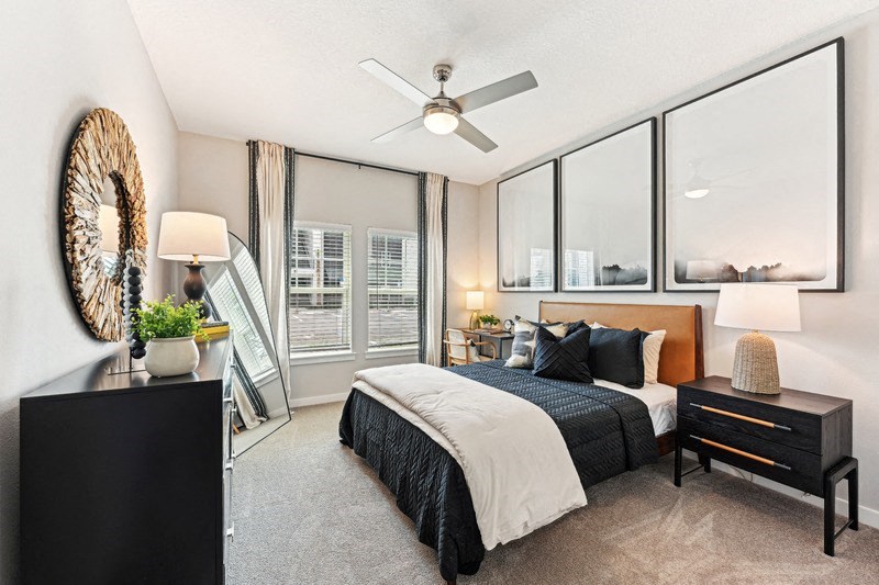 a bedroom with a large window and a ceiling fan