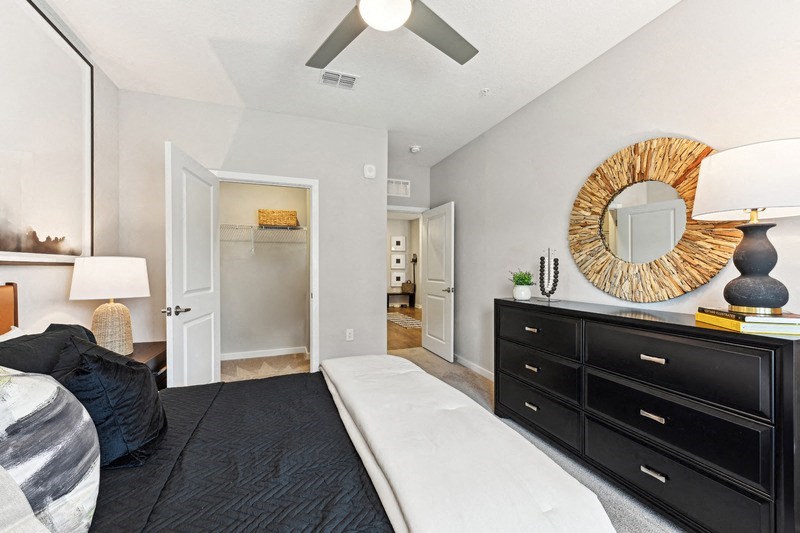a bedroom with a bed and a dresser and a ceiling fan
