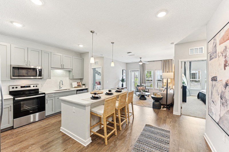 A kitchen with a white island and wooden chairs.