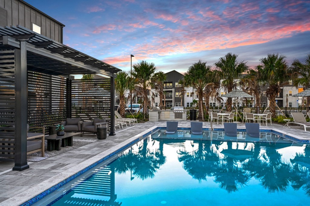 A pool with a reflection of a building and palm trees.