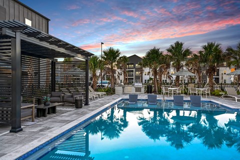 A pool with a reflection of a building and palm trees.