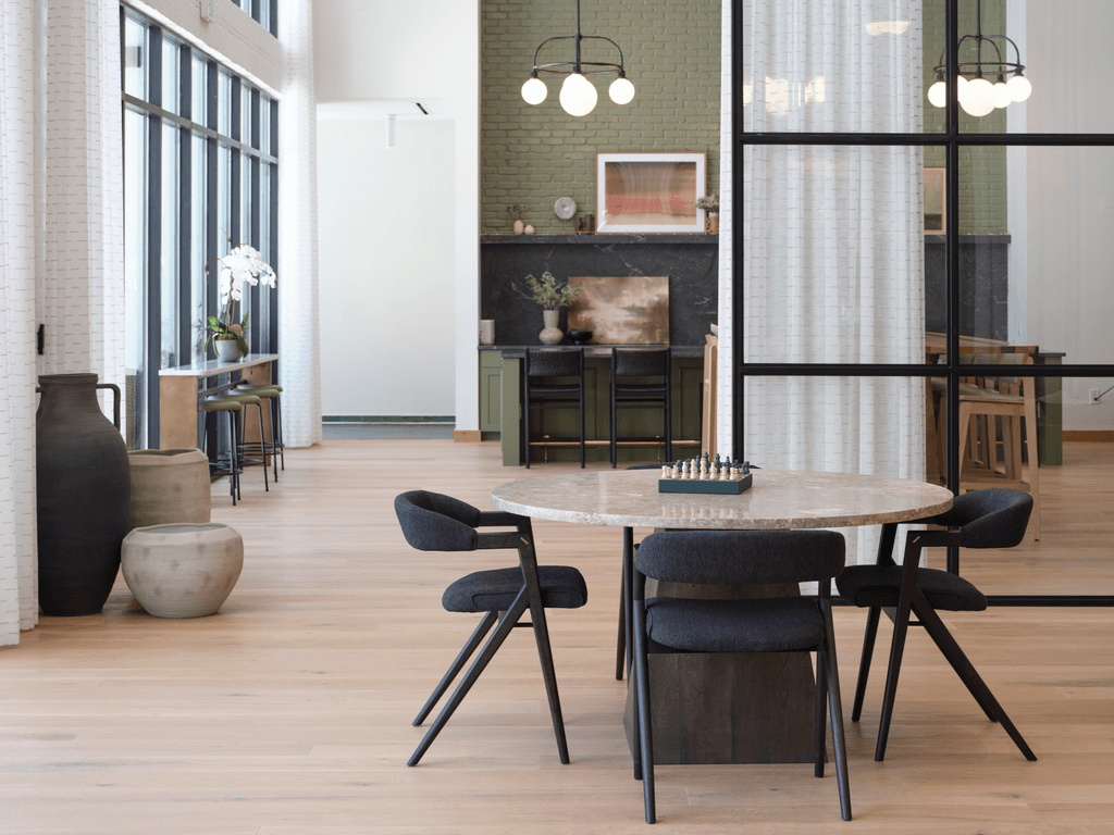 A modern dining room with a white table and black chairs.