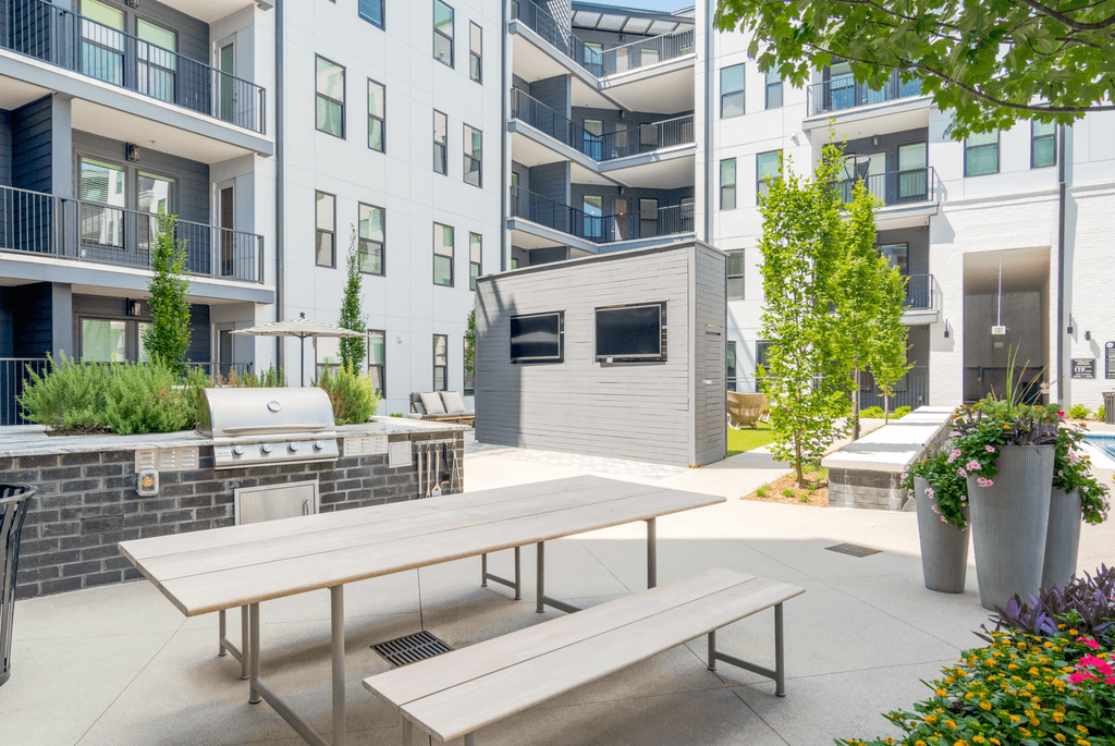 A patio with a table and chairs is surrounded by apartment buildings.