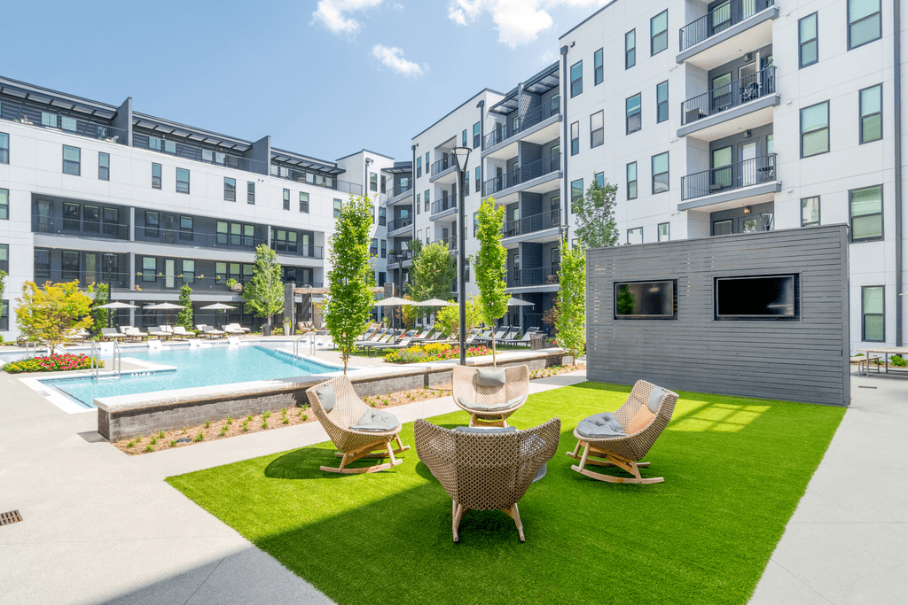 A modern outdoor seating area with a pool and buildings in the background.