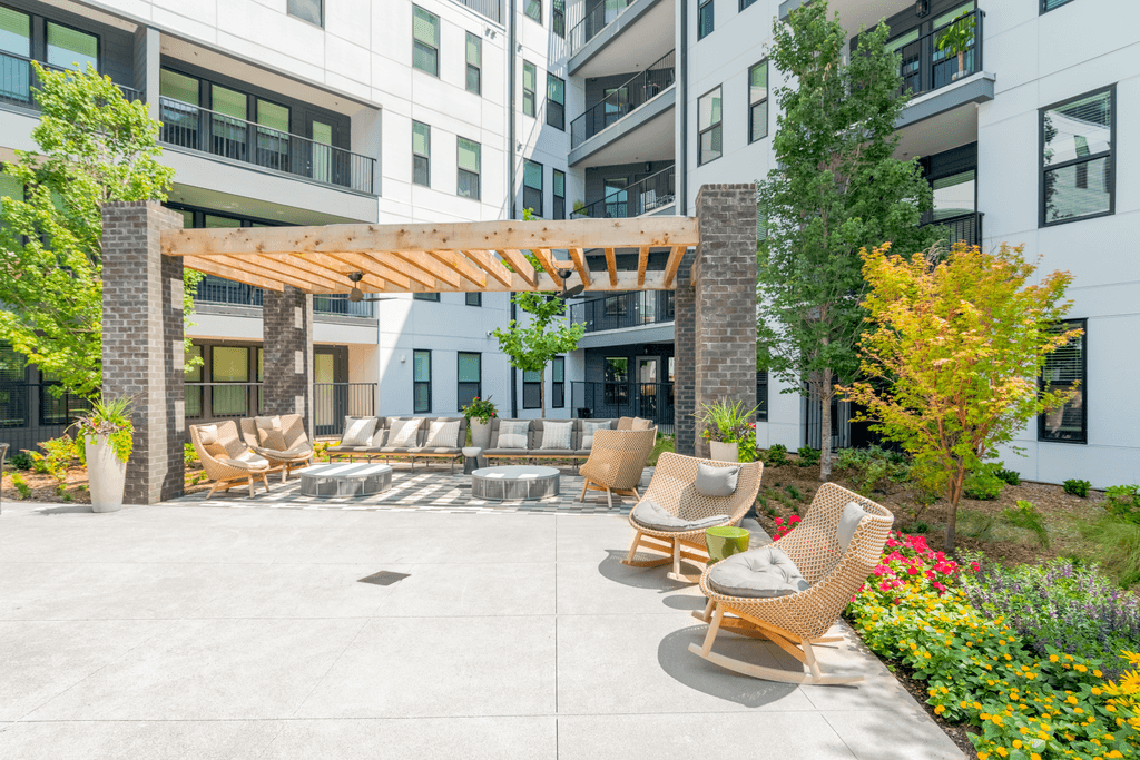 A patio with chairs and a pergola in front of a building.