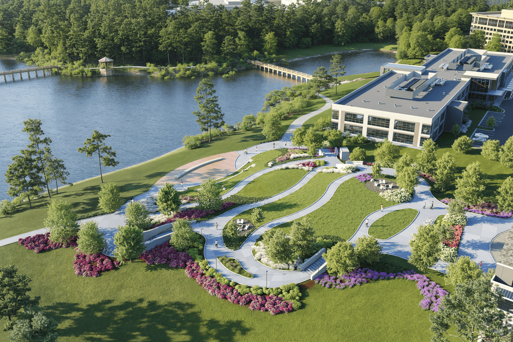 A large building sits on a lush green hillside next to a body of water.