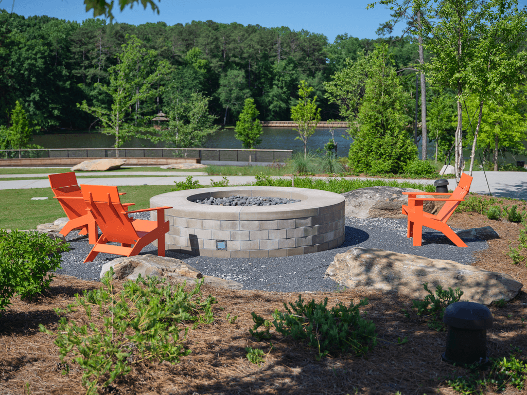 A fire pit surrounded by orange chairs in a backyard setting.